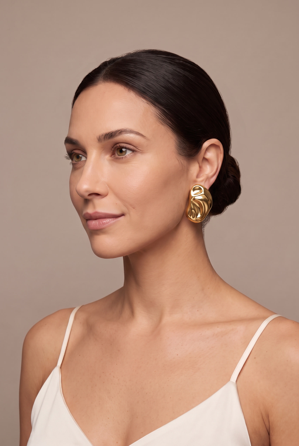 Molten bean stud earring in gold worn on the ear