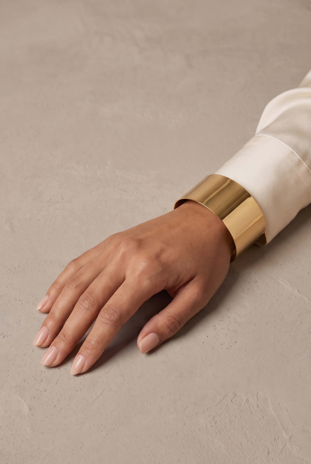 Plain wide polished cuff bangle in gold worn on the wrist